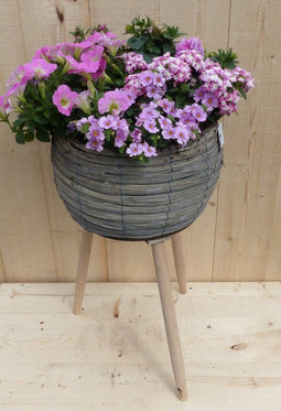 Rieten plantenbak grijs op poten met zomerbloeiers roze h55 cm